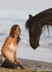 Ojai, CA, purebred horse, black Friesian gelding with owner at the beach