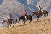 Flitner Ranch, Shell, WY - two cowboys and cowgirl riding down a hill