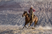 Flitner Ranch, Shell, WY - cowboy runs down hill and turns