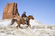 cowboy on sorrel Quarter horse running in the snow at Flitner Ranch, Shell, WY