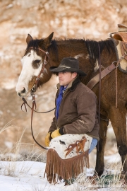 Flitner Ranch, Shell, WY, horses in winter, cowboy squats next to his horse