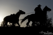 Sombrero Ranch, Craig, CO, cowboy leading pack horse in silhouette
